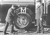 The driver uses a lever to raise the road wheel on the eccentric, the man on the right holds one of the holding pins