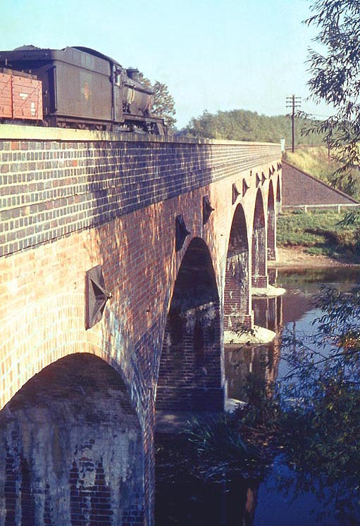 Ex-GWR 4-6-0 Hall class No 6940 'Didlington Hall' is seen passing over the River Avon on a freight service to Fenny Compton