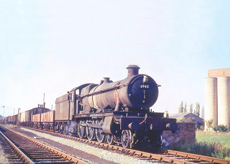 Ex-GWR 4-6-0 Hall class No 6940 'Didlington Hall' is seen passing through Stratford on Avon station at the head of an up freight service