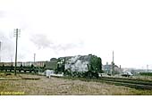 An unidentified BR 9F 2-10-0 locomotive is seen with a Class H through freight of coal in the early 1960s