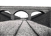 A line of contractor's temporary track snakes under a brick occupation overbridge near Staverton