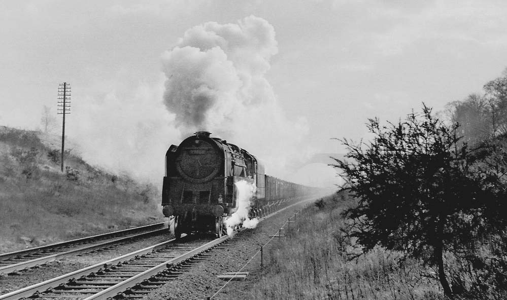 An unidentified British Railway's Standard Class 9F is seen working hard at the head of a Class F express freight south of Rugby Central