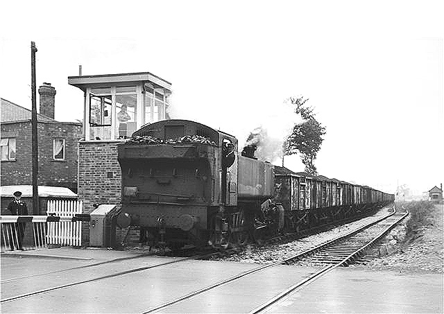British Railways built 0-6-0T No 1501 is seen running tender first at the head of a long coal train as it crosses Wheelwright Lane level crossing