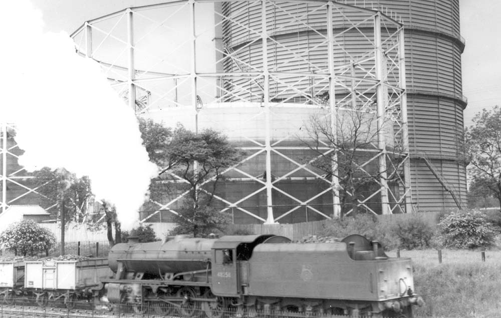 Ex-LMS 2-8-0 8F No 48258 is seen running tender first past Foleshill gasometers whilst at the head of a coal train
